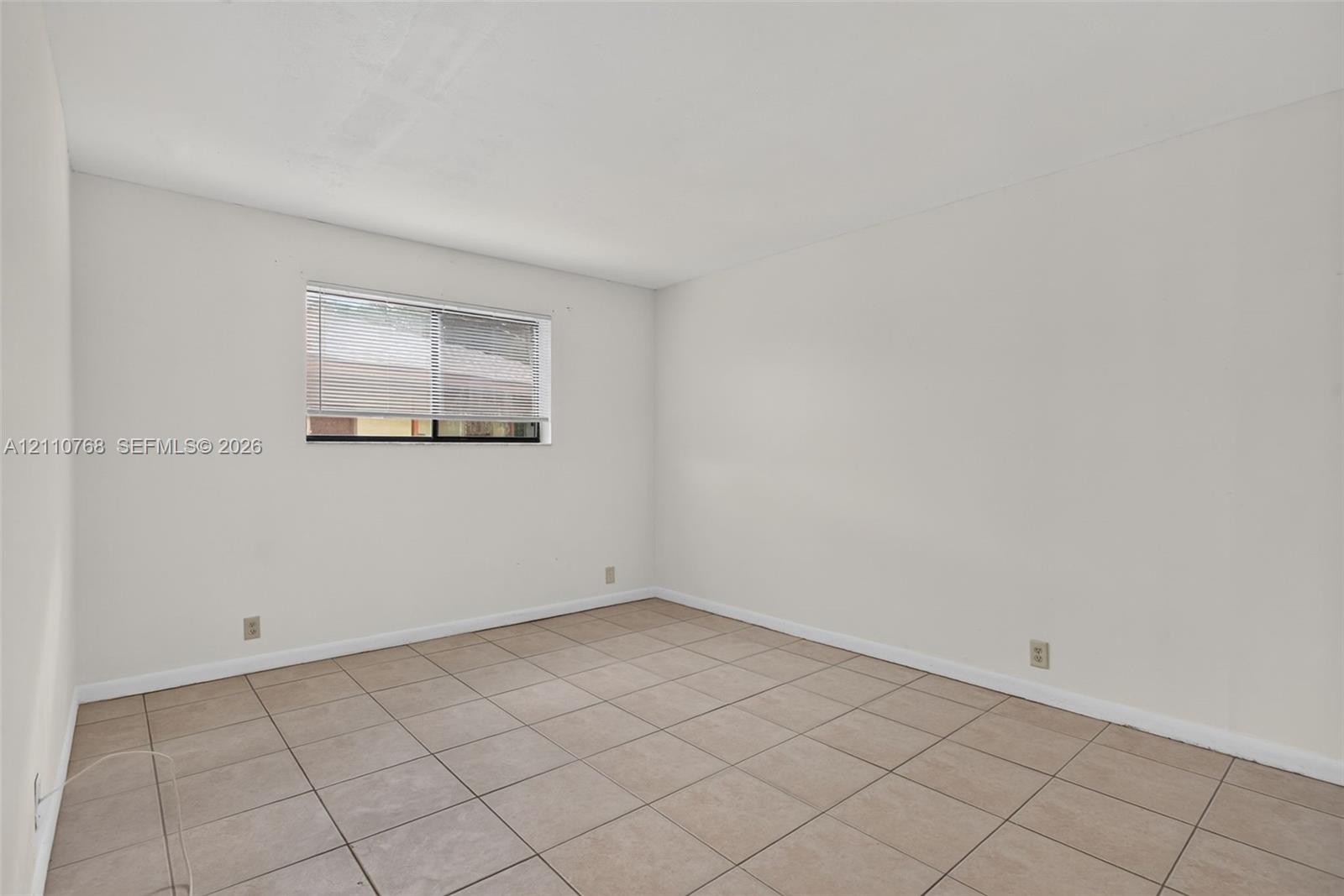 Neutral interior space featuring ceramic tile flooring, neutral wall tones, and a single sliding window