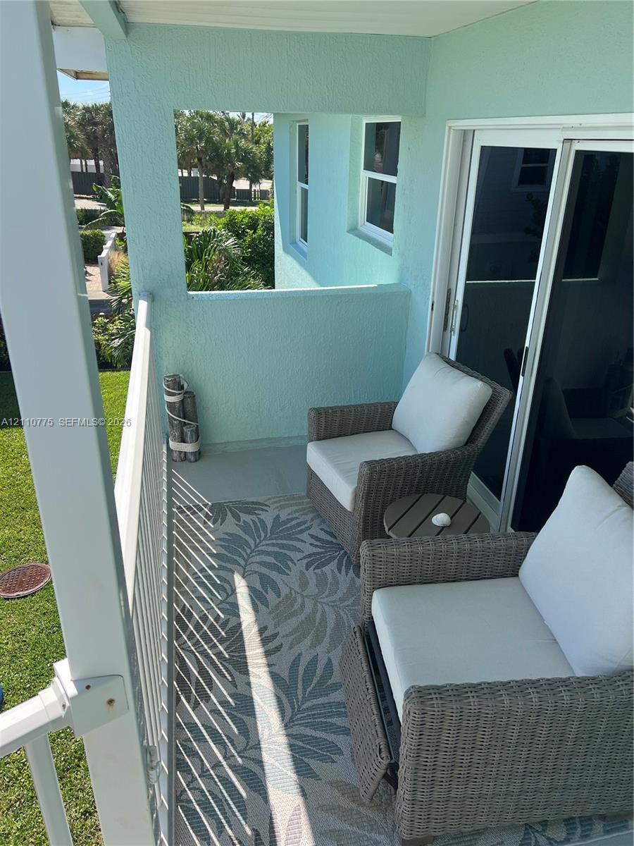 Private balcony featuring stucco walls, a metal railing, and sliding glass door access Private balcony featuring stucco walls, a metal railing, and sliding glass door access