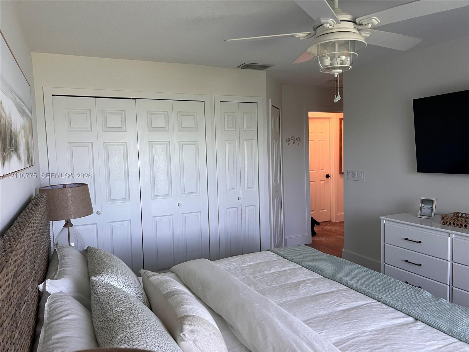 Primary bedroom featuring paneled bi-fold closet doors and a ceiling-mounted fan with integrated light fixture