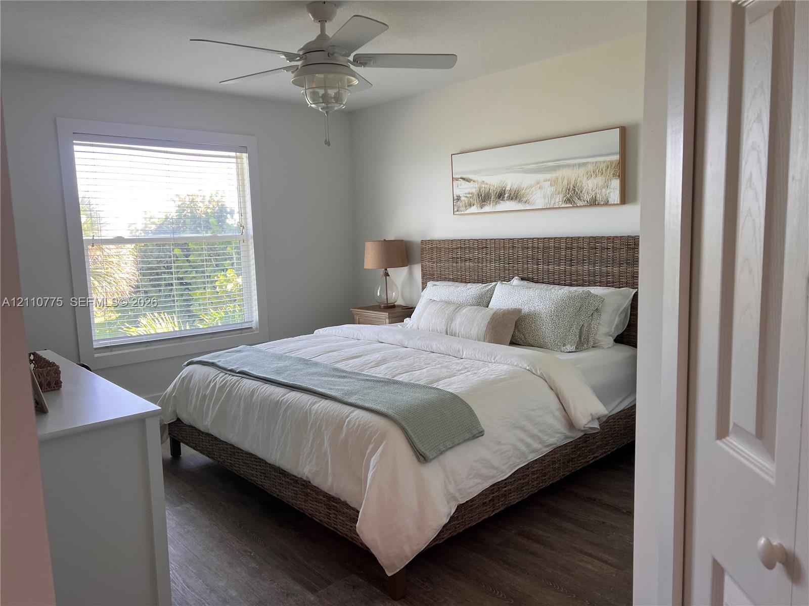 Wood-finish flooring, ceiling fan with integrated lighting, and window with horizontal blinds Wood-finish flooring, ceiling fan with integrated lighting, and window with horizontal blinds
