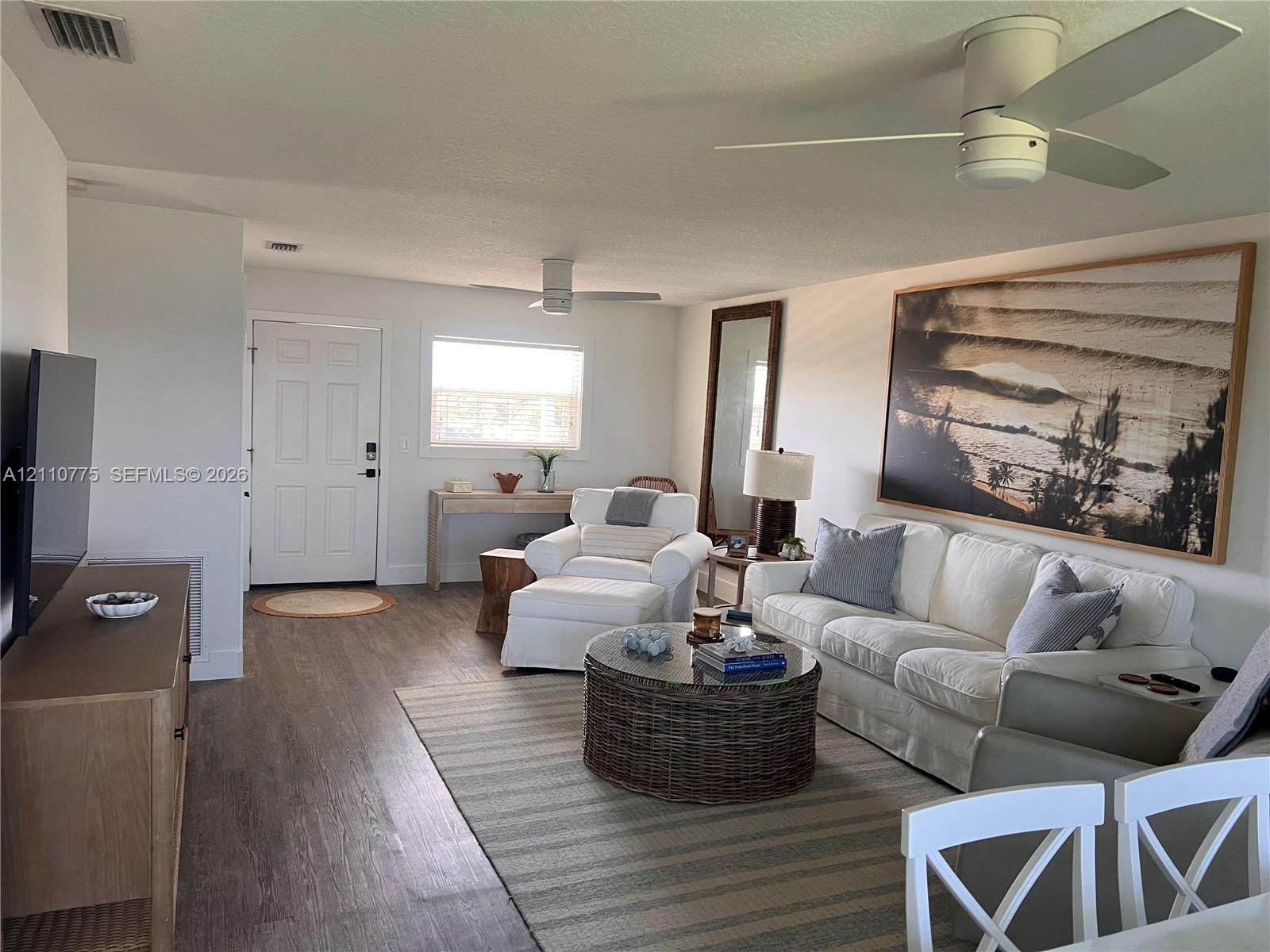 Open-concept room featuring wood-finish flooring, neutral wall paint, and dual ceiling fans