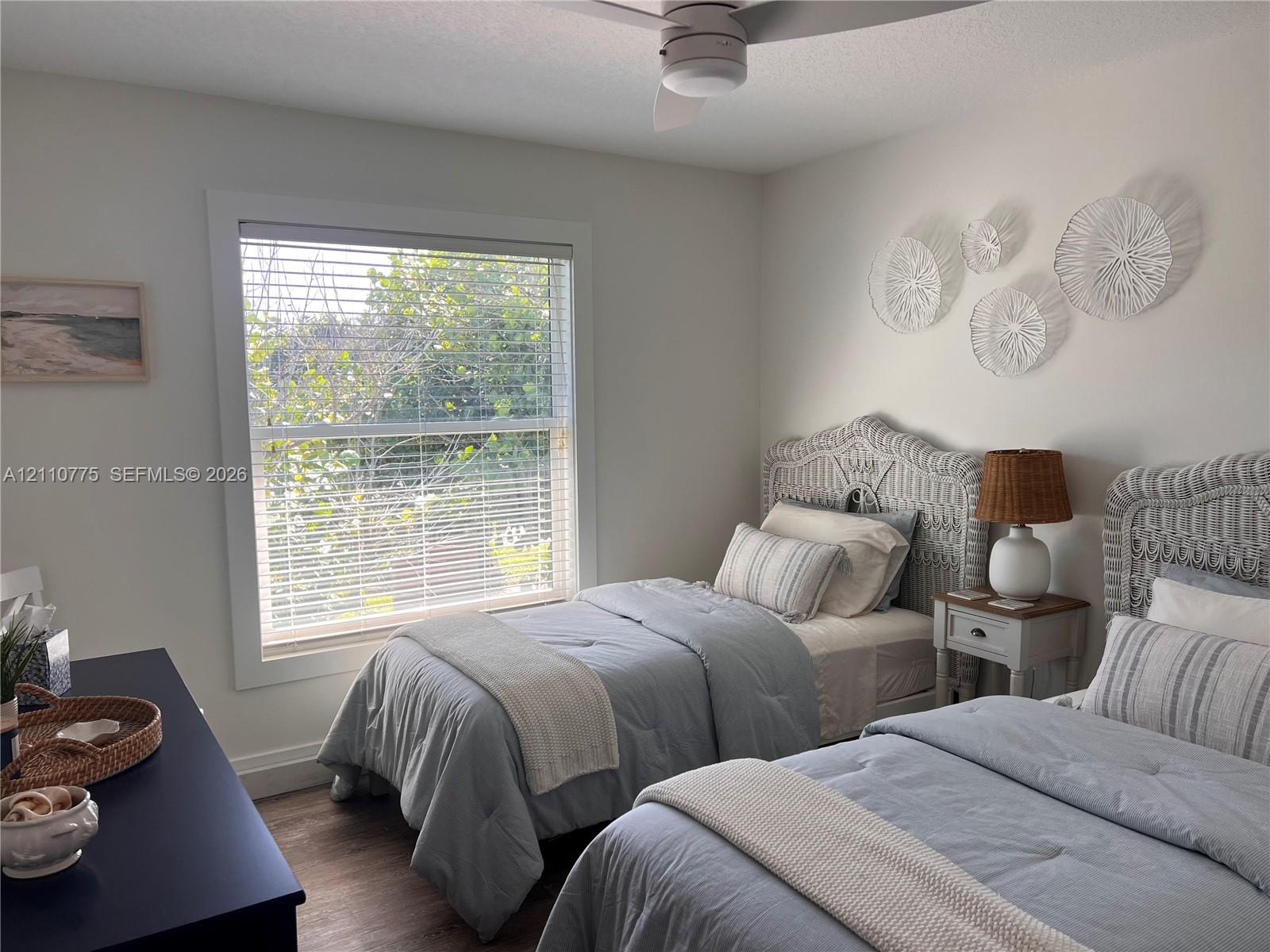 Large window with white casing, wood-finish flooring, and ceiling-mounted fan with integrated lighting