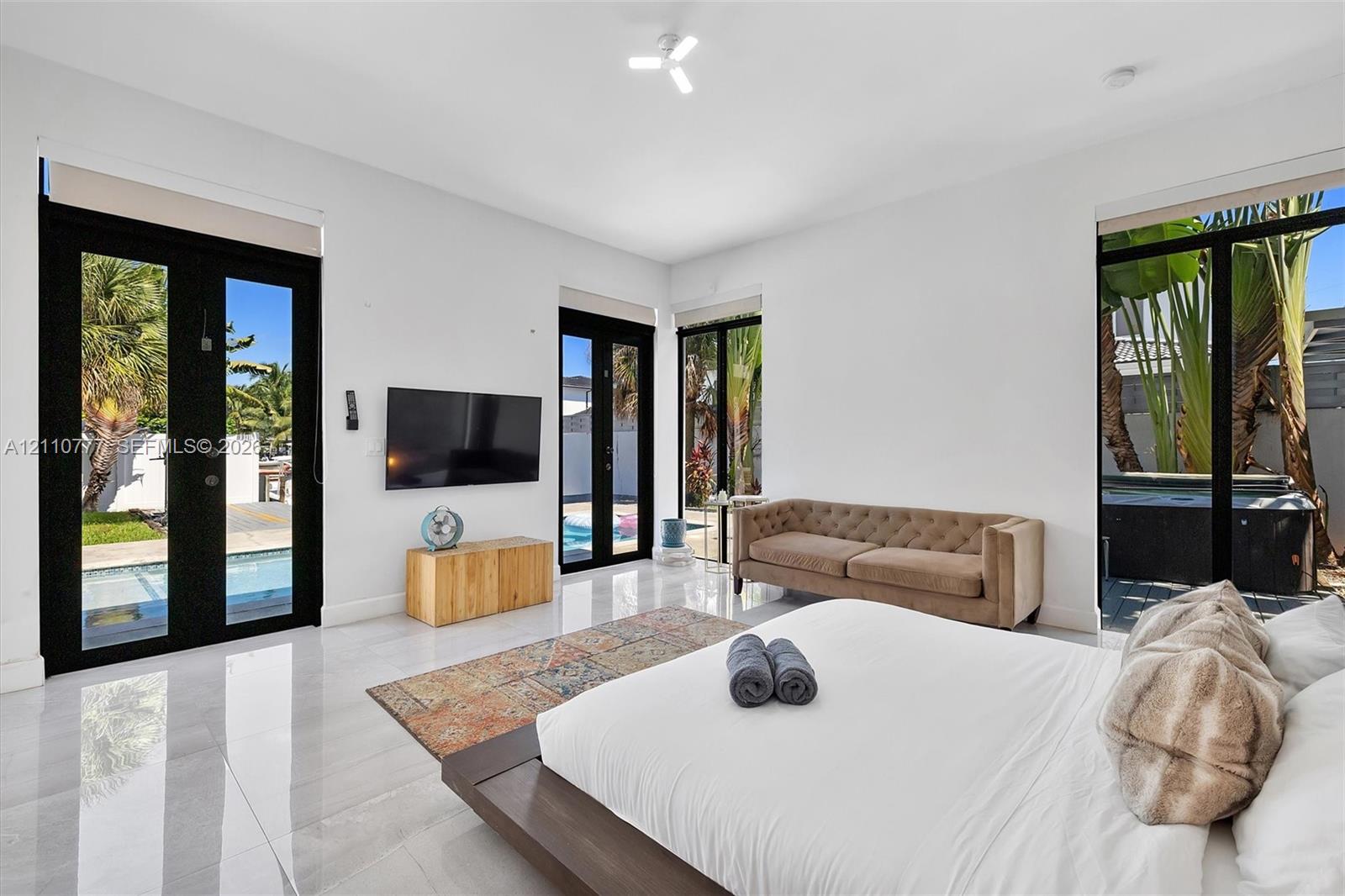 Polished tile flooring, high ceilings, and multiple black-framed glass panel doors providing exterior access