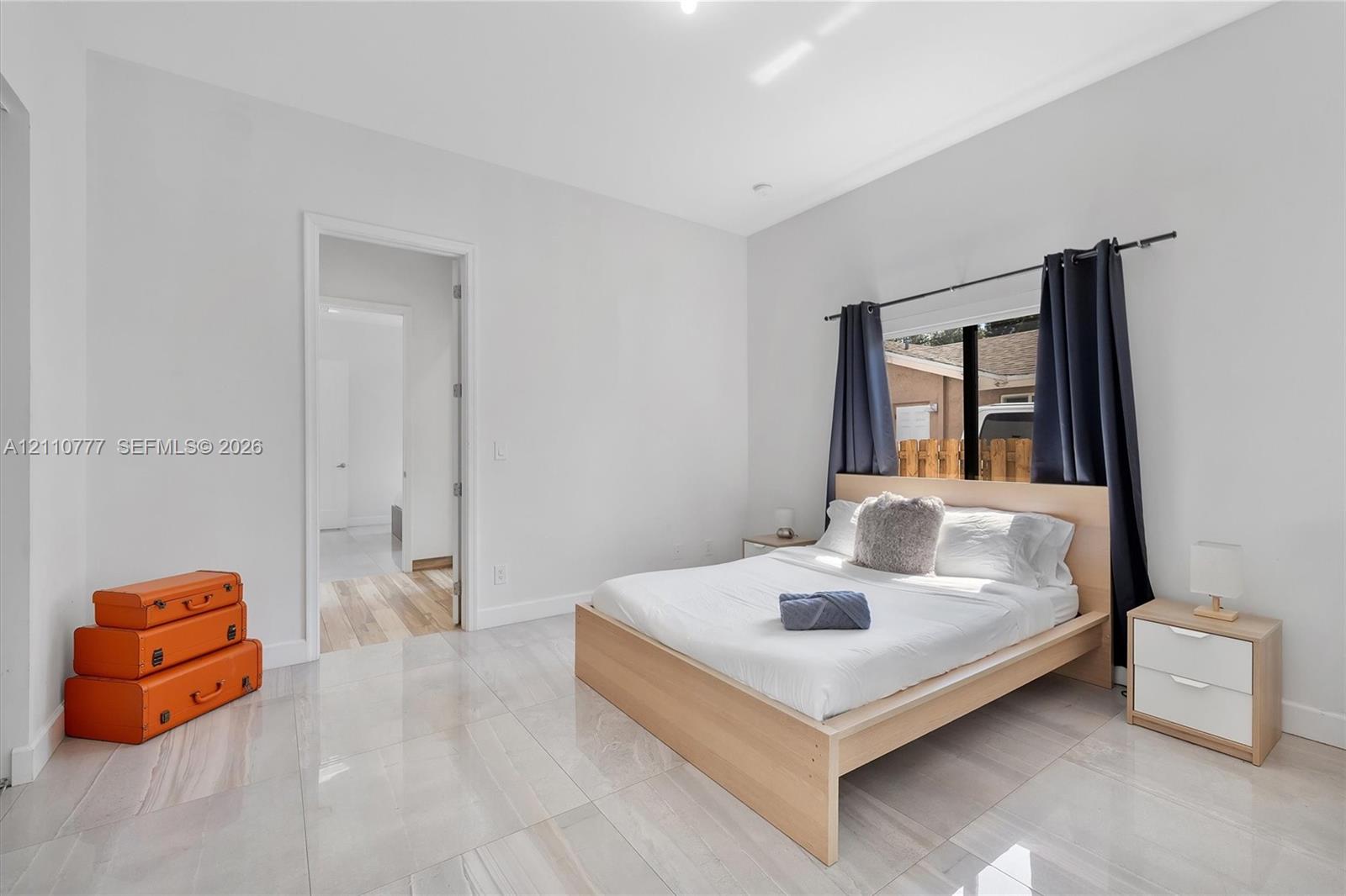 Neutral-toned oversized tile flooring, high ceilings, and a window with black metal hardware