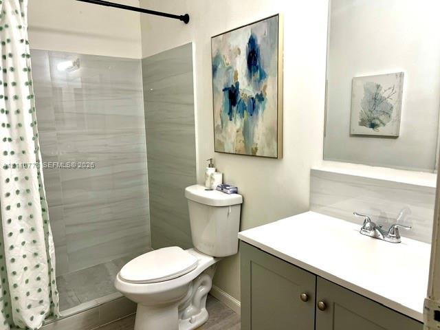 Bathroom featuring a vanity with a white countertop, large wall-mounted mirror, and walk-in shower with horizontal tile surround
