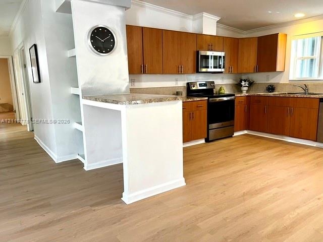 Kitchen featuring wood-finish cabinetry, stone-surface countertops, stainless steel appliances, and wood-finish flooring