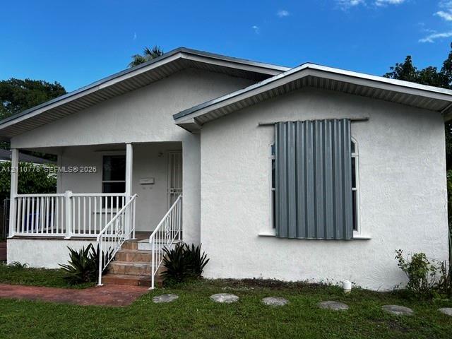 Stucco exterior with a covered front porch, white metal railing, and stone-tiled stairs