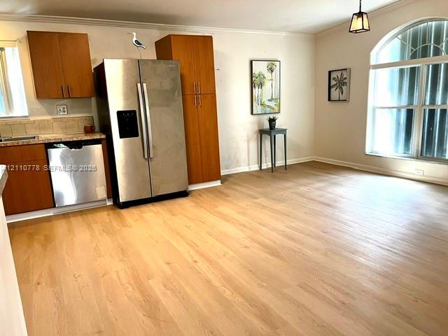 Kitchen featuring wood-finish cabinetry, stainless steel side-by-side refrigerator, stainless steel dishwasher, wood-finish flooring, and a large arched window