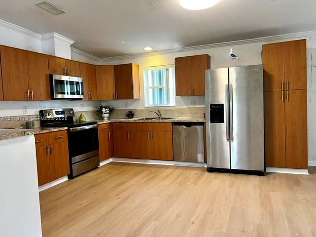 Kitchen featuring wood-finish cabinetry, neutral solid-surface countertops, stainless steel appliances, and wood-finish flooring