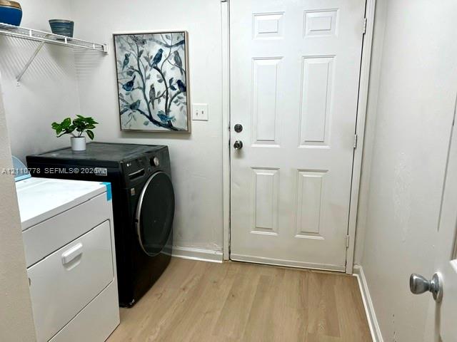 Laundry space featuring wood-finish flooring, a six-panel exterior door, and an installed wire shelving unit