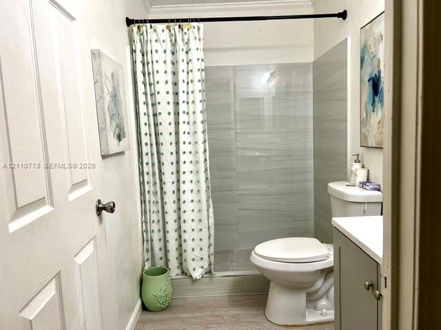 Bathroom featuring a walk-in shower with grey horizontal-tile surround, vanity with stone-top surface, and wood-finish flooring