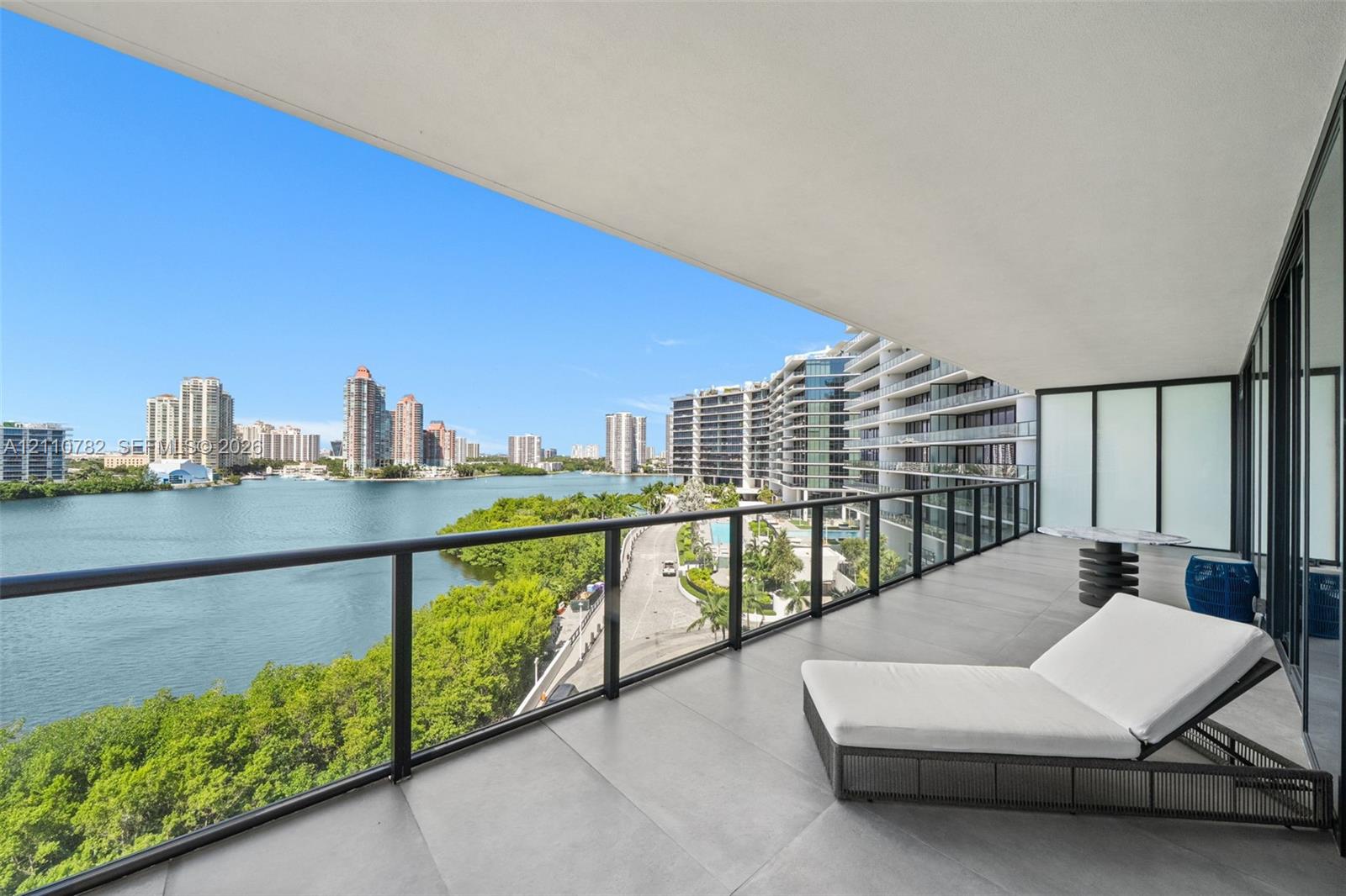 Expansive covered balcony featuring large-format porcelain tile flooring and a black metal railing with glass inserts