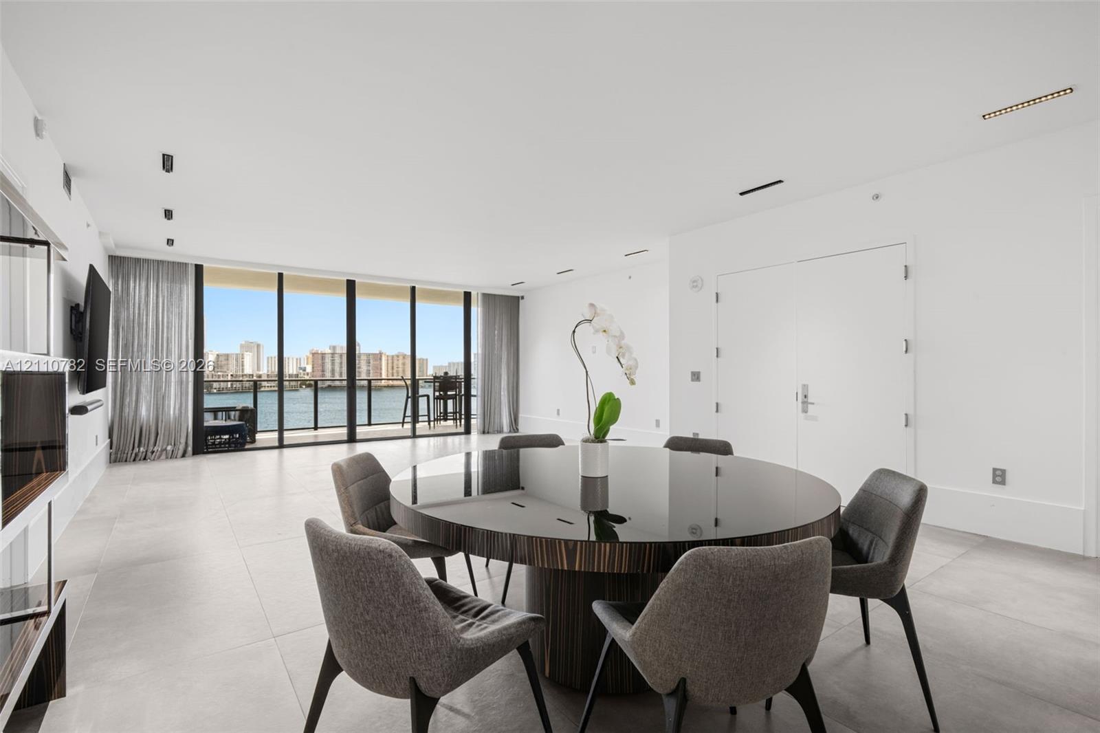 Open-concept interior featuring large-format tile flooring, floor-to-ceiling glass panel windows, integrated recessed lighting, and a private balcony Open-concept interior featuring large-format tile flooring, floor-to-ceiling glass panel windows, integrated recessed lighting, and a private balcony