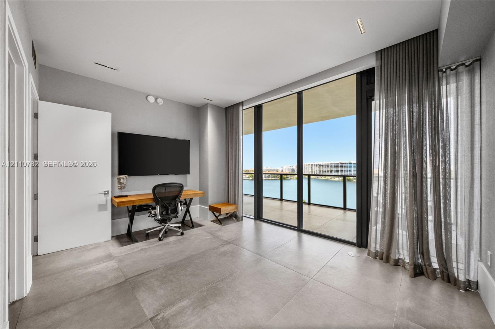 Floor-to-ceiling glass wall, large-format tile flooring, recessed ceiling lighting, and covered balcony featuring a glass panel railing