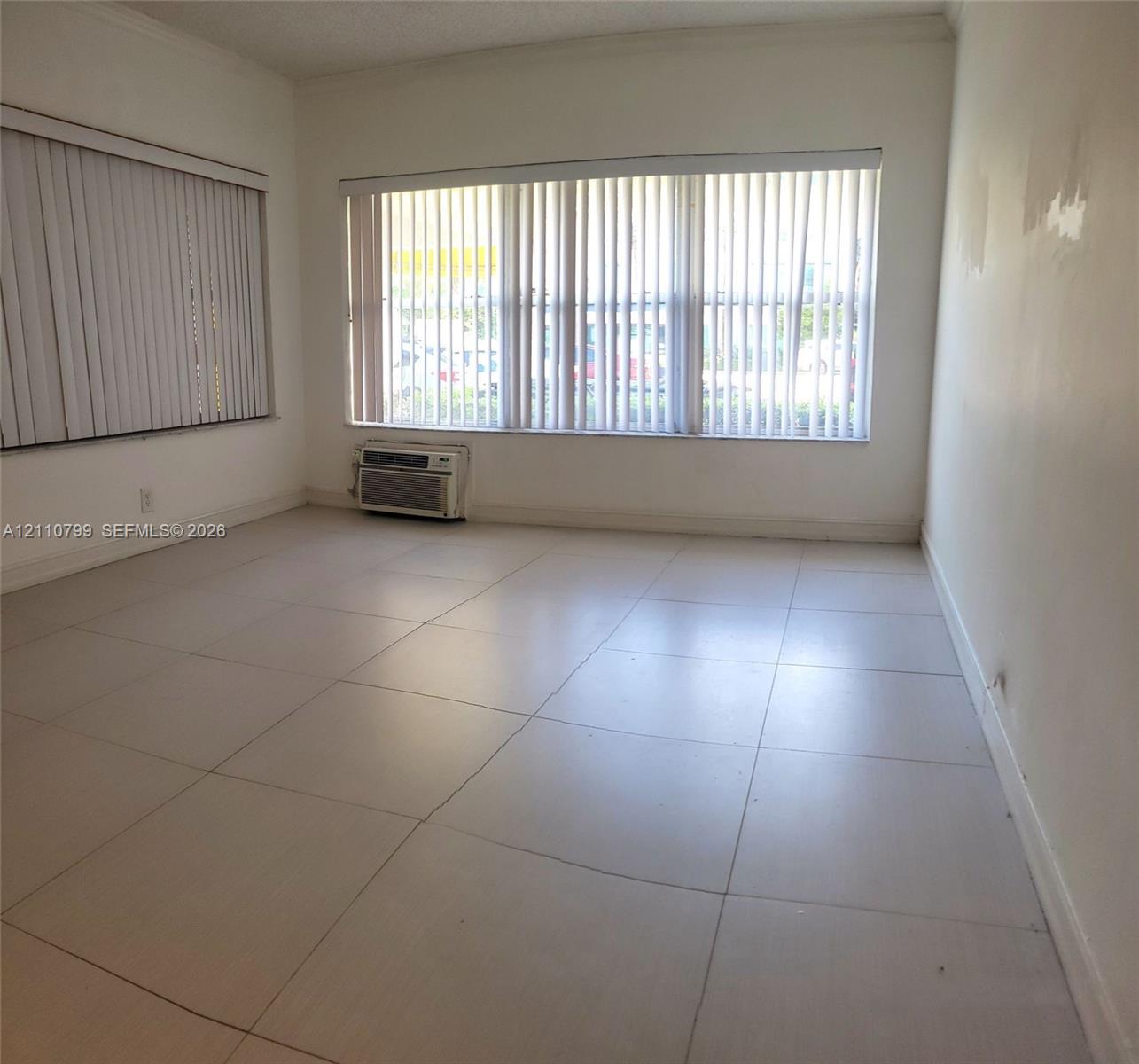 Large-format ceramic floor tiling, multiple expansive windows with integrated vertical blinds, and a wall-mounted air conditioning unit Large-format ceramic floor tiling, multiple expansive windows with integrated vertical blinds, and a wall-mounted air conditioning unit