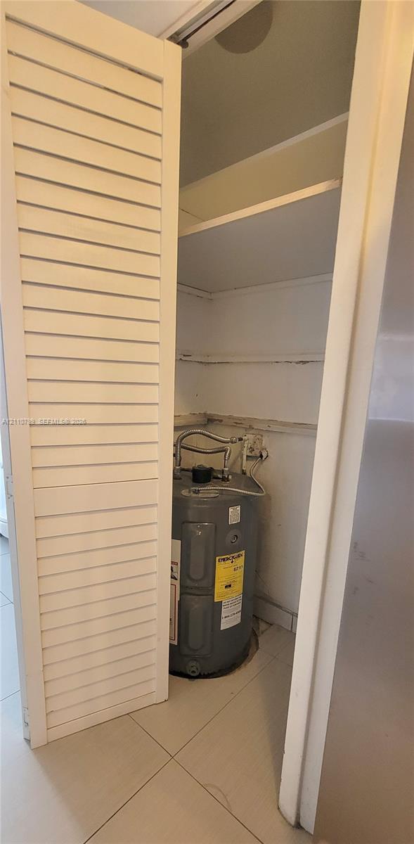 Utility closet featuring louvered bi-fold doors, tile flooring, and integrated white shelving Utility closet featuring louvered bi-fold doors, tile flooring, and integrated white shelving