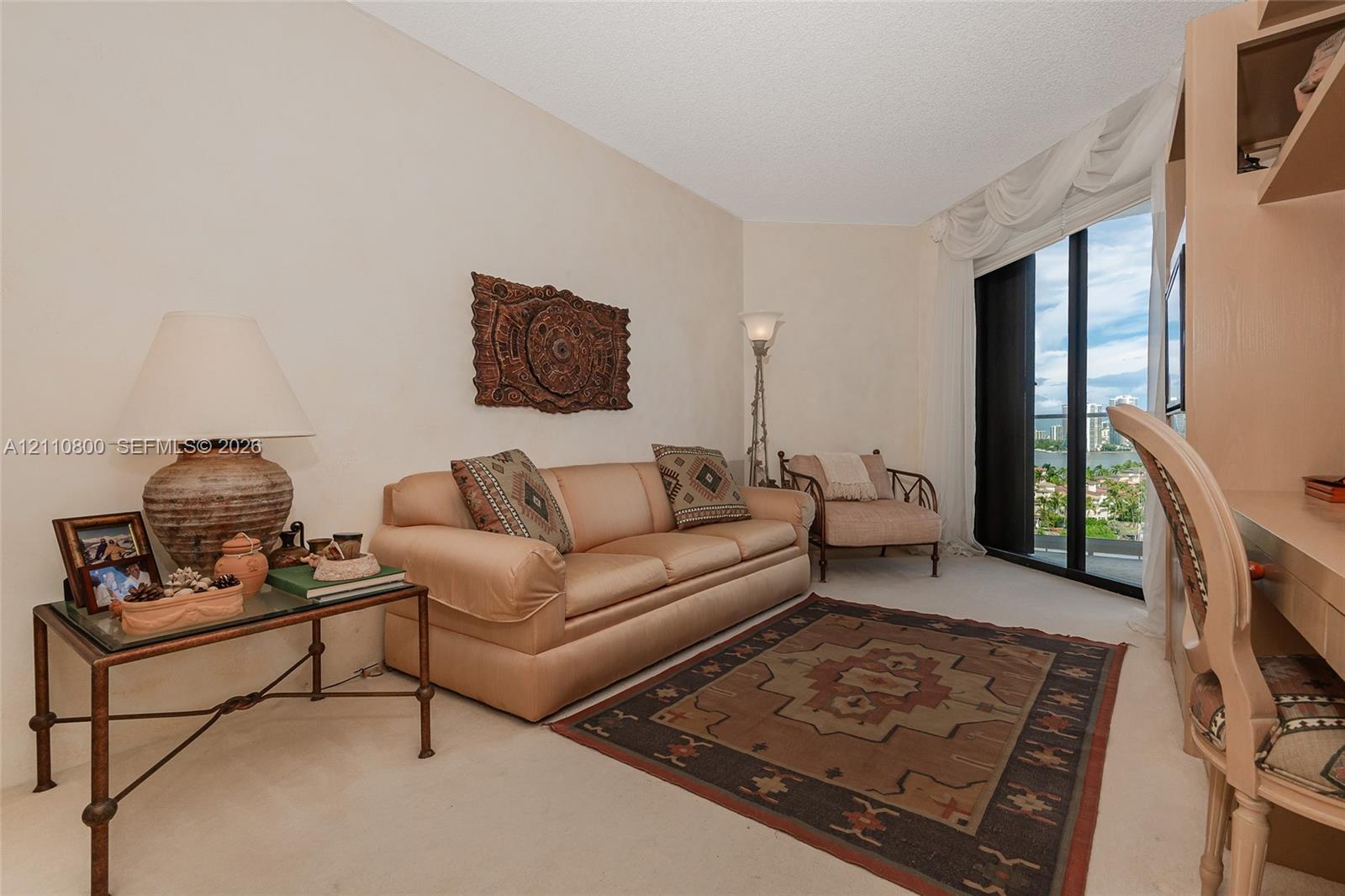 Living area featuring floor-to-ceiling glass sliding doors, built-in desk cabinetry, and carpeted flooring