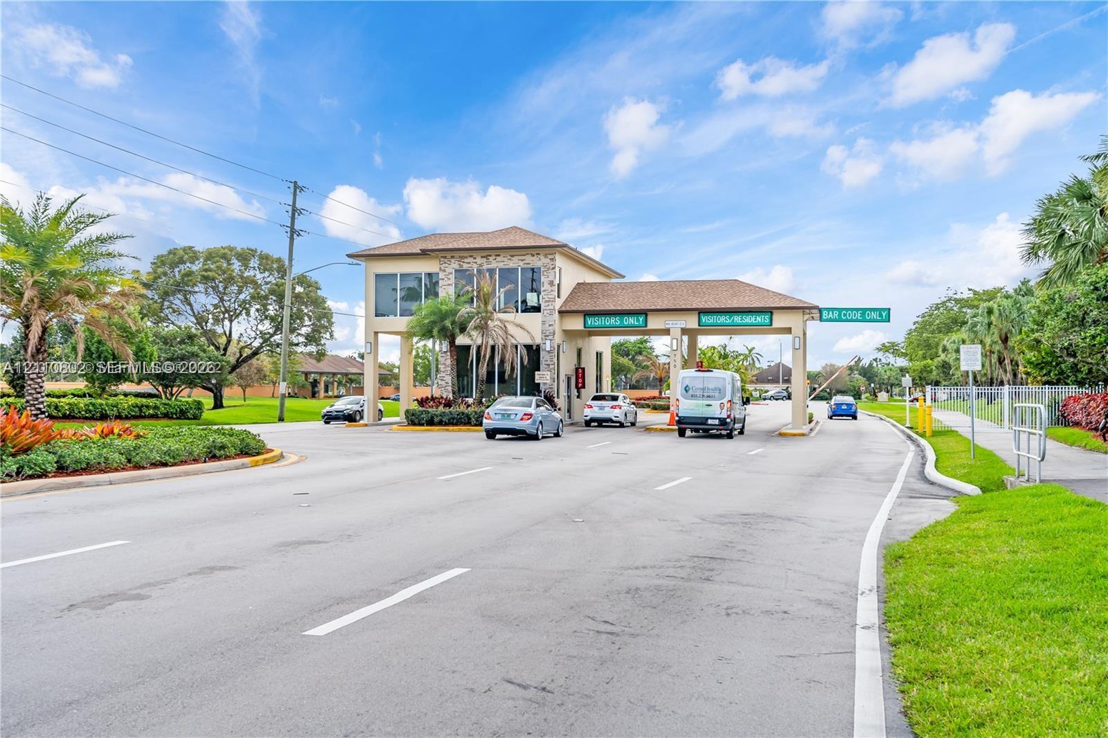 Gated entry structure featuring stone masonry siding, multi-lane access points, and dedicated visitor and resident traffic signage