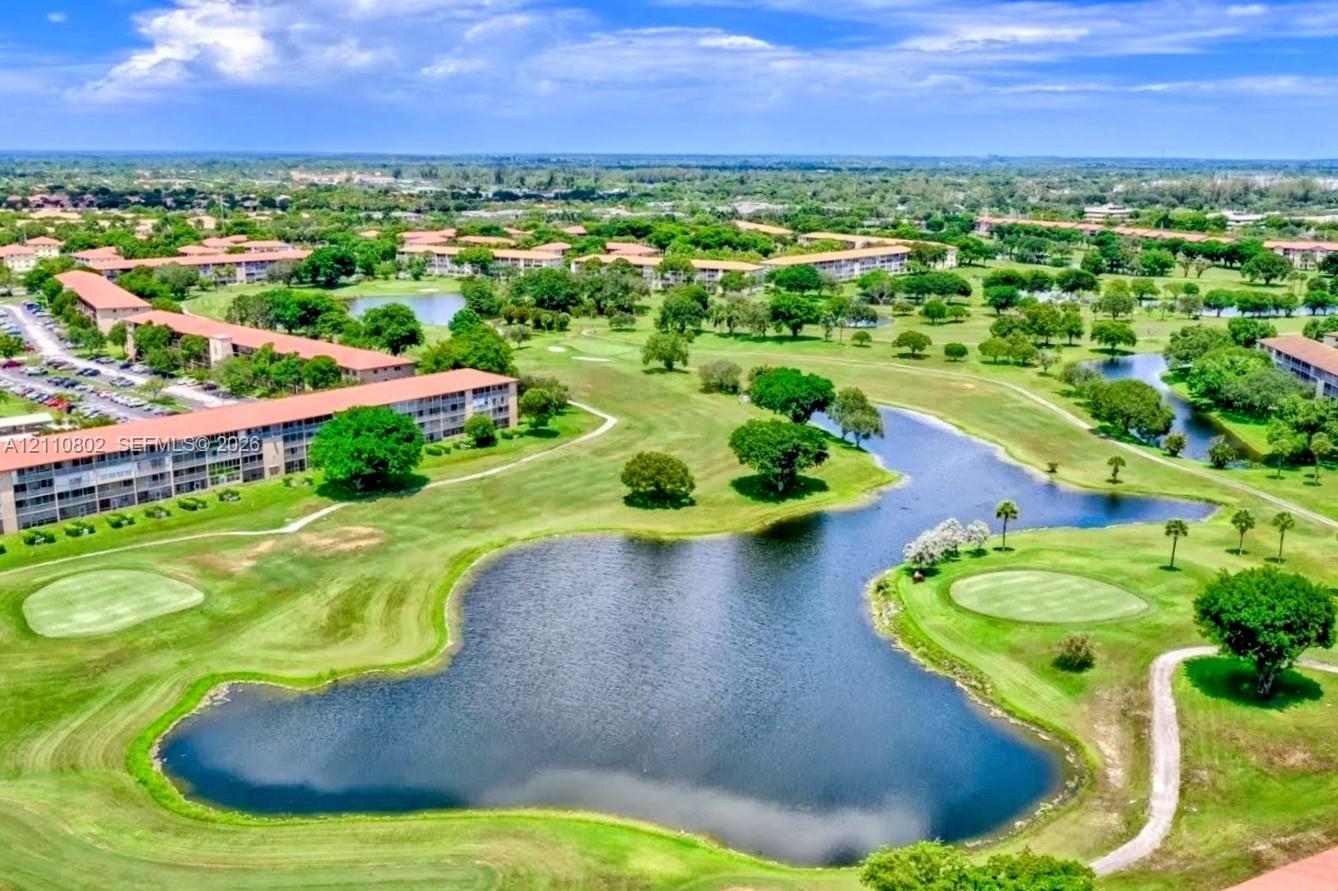 Aerial perspective of multi-unit residential structures overlooking expansive golf course grounds featuring manicured fairways, water hazards, and mature landscaping