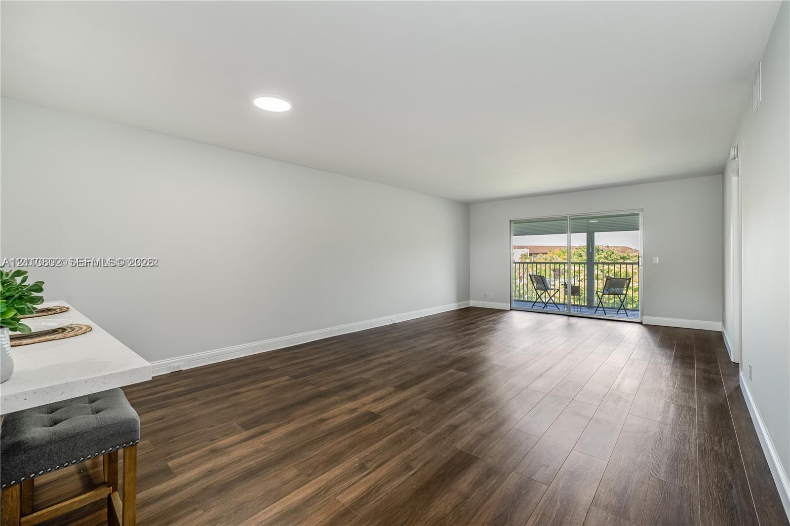 Open-concept living space featuring wood-finish flooring, recessed lighting, and sliding glass doors with exterior access Open-concept living space featuring wood-finish flooring, recessed lighting, and sliding glass doors with exterior access