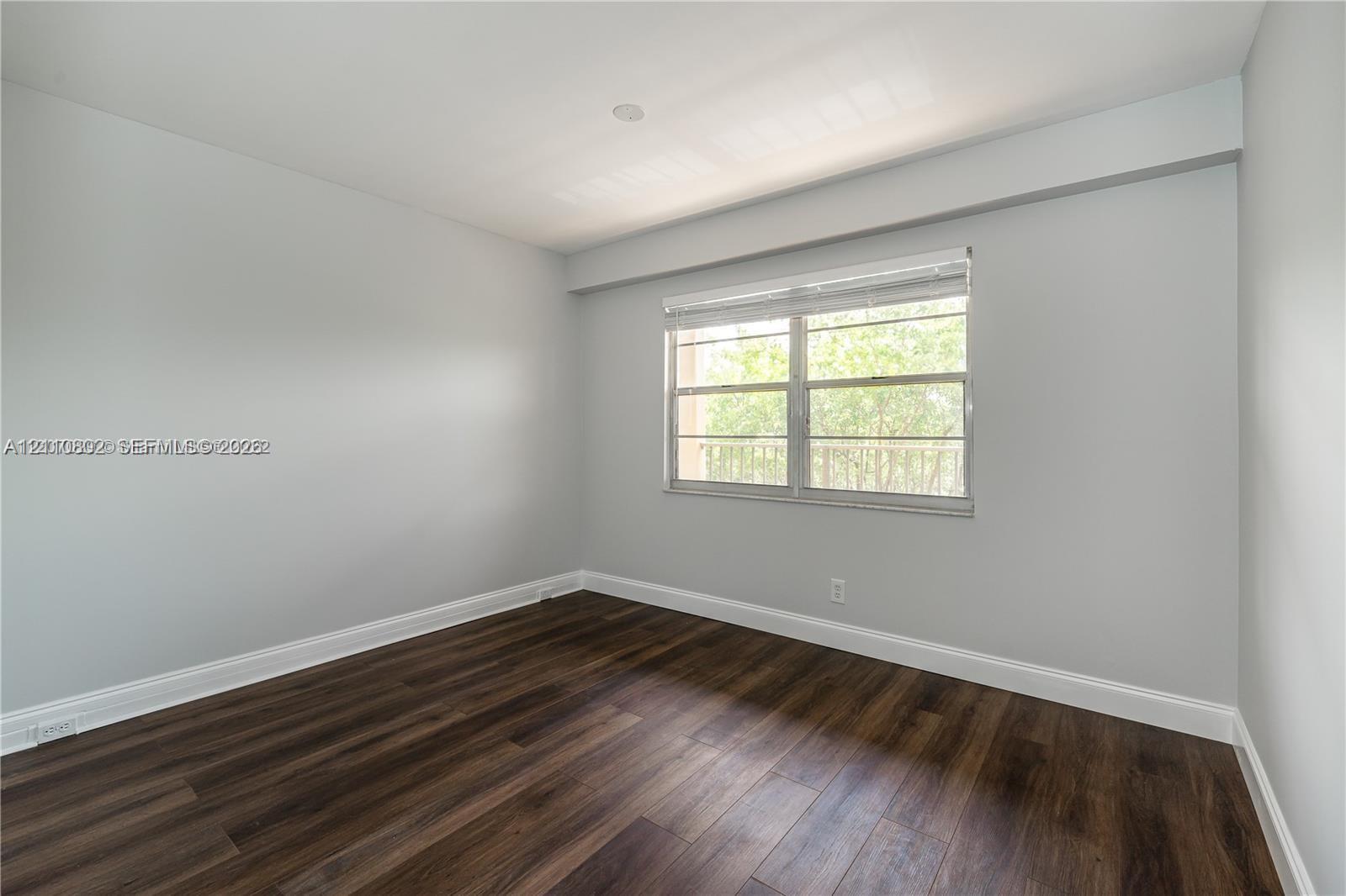Neutral-toned walls, wood-finish flooring, and a window with horizontal blinds