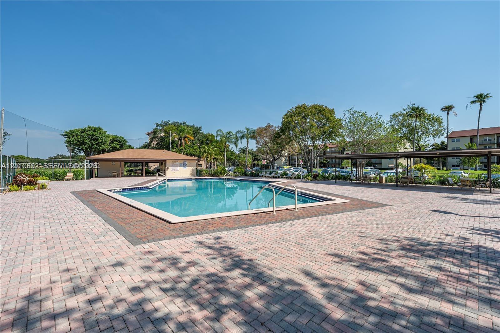 Swimming pool with stone-tiled decking, covered pavilion, and metal-framed shade structure