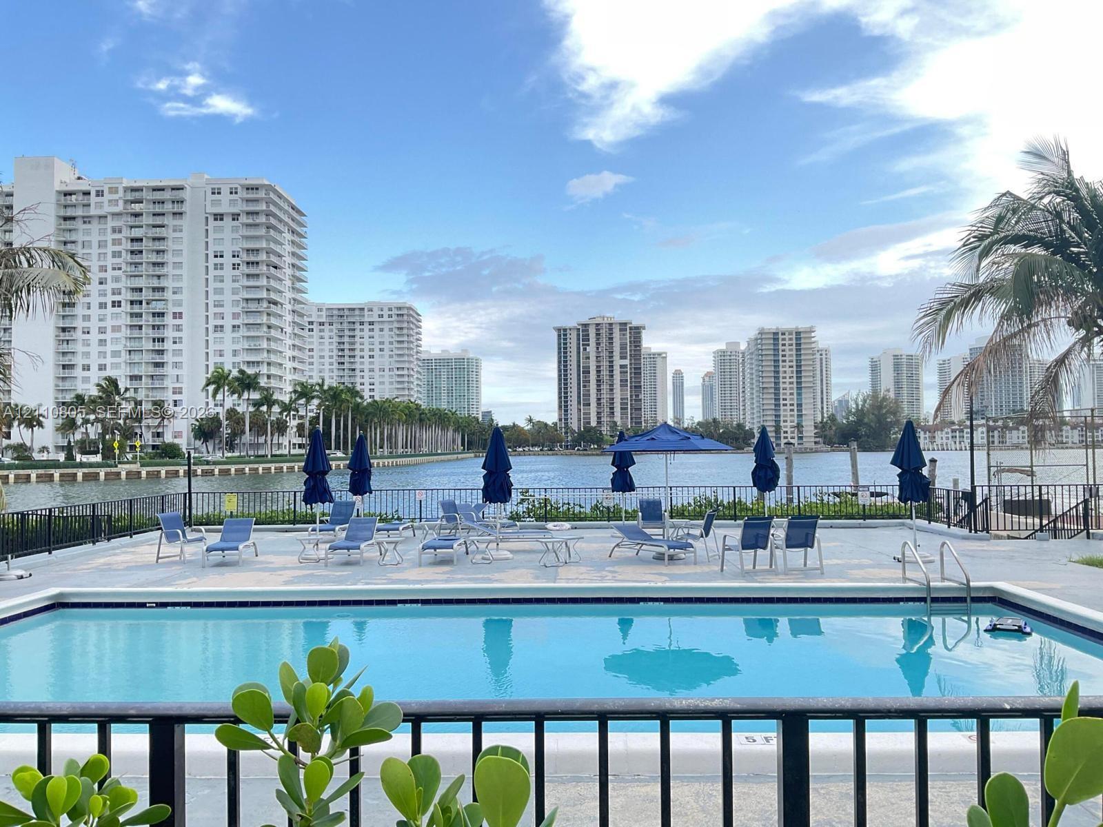 Swimming pool featuring concrete decking, a metal perimeter fence, and direct water frontage