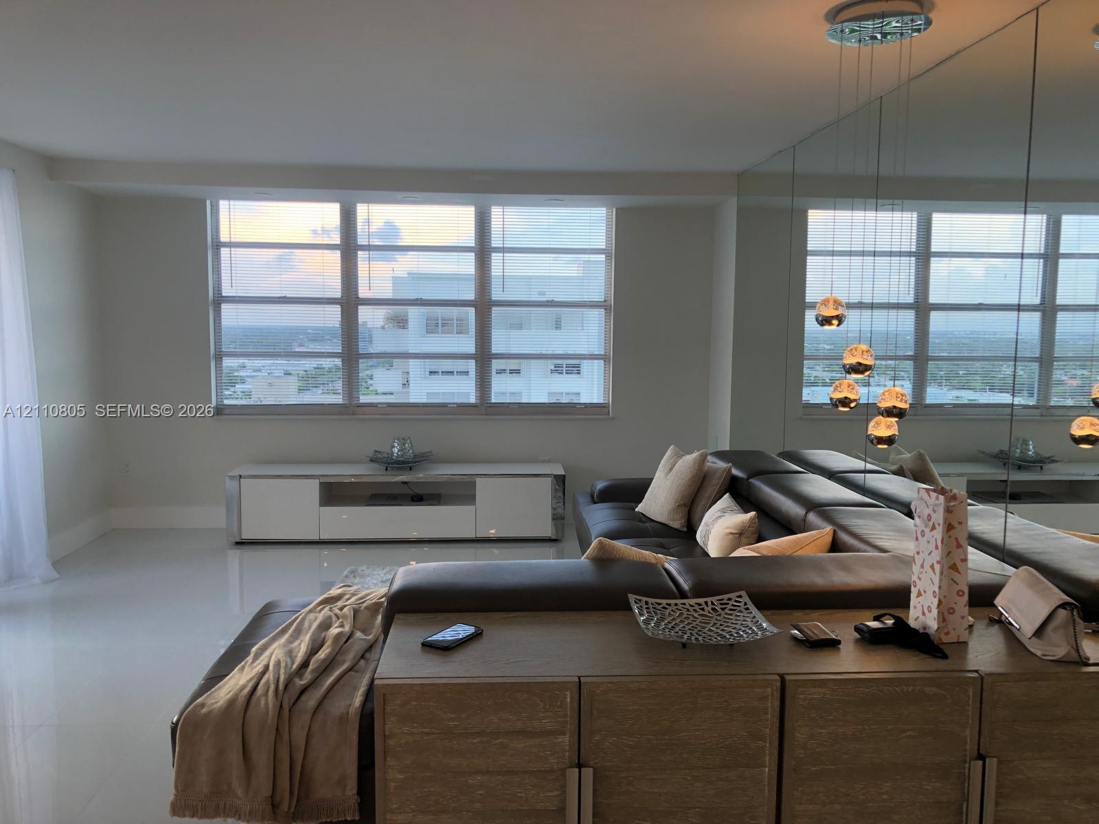 Large-format light-toned tile flooring, floor-to-ceiling wall mirror, multi-pane picture windows, and pendant globe lighting Large-format light-toned tile flooring, floor-to-ceiling wall mirror, multi-pane picture windows, and pendant globe lighting