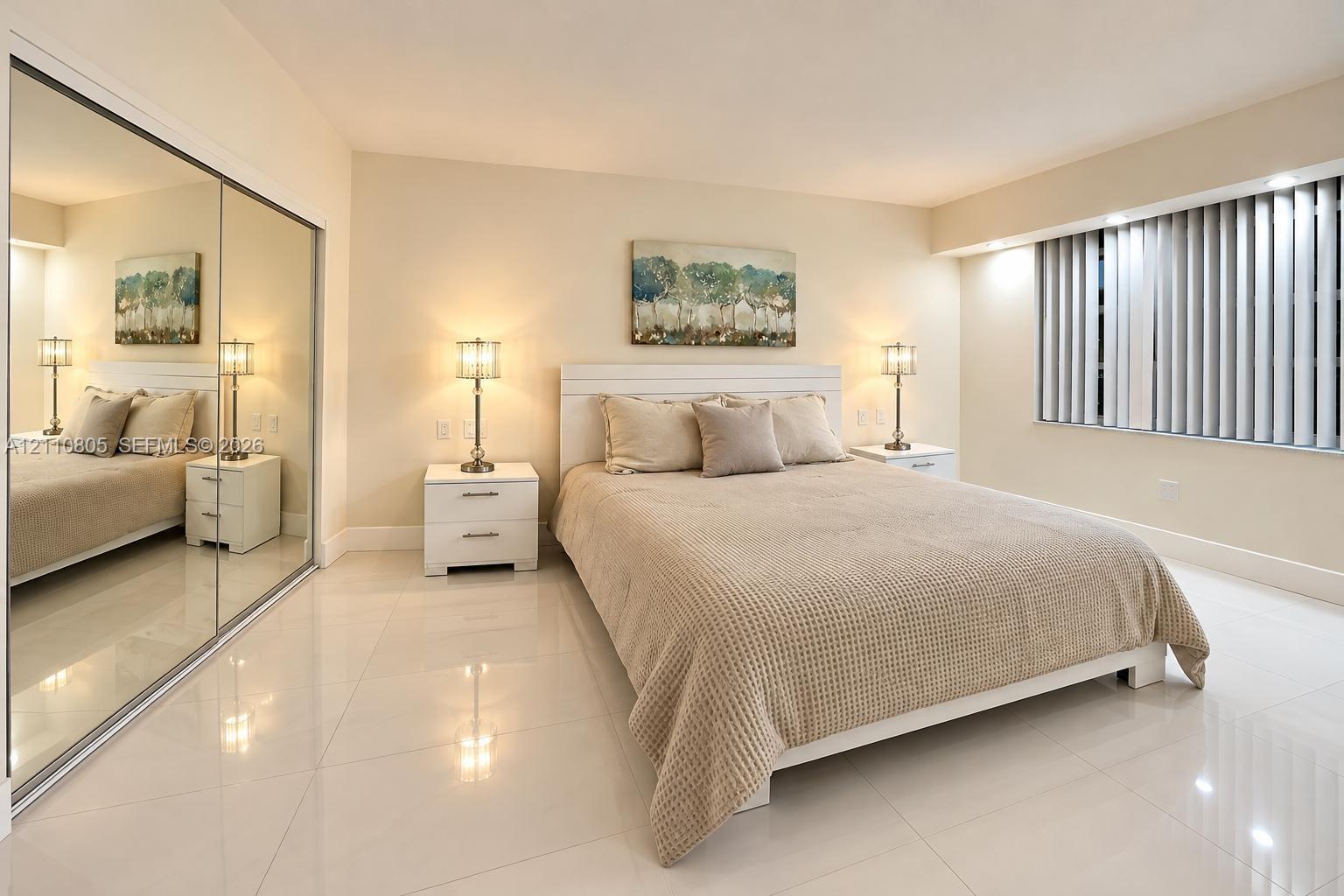 Large-format polished tile flooring, full-height sliding mirrored closet doors, and a recessed window featuring vertical blinds