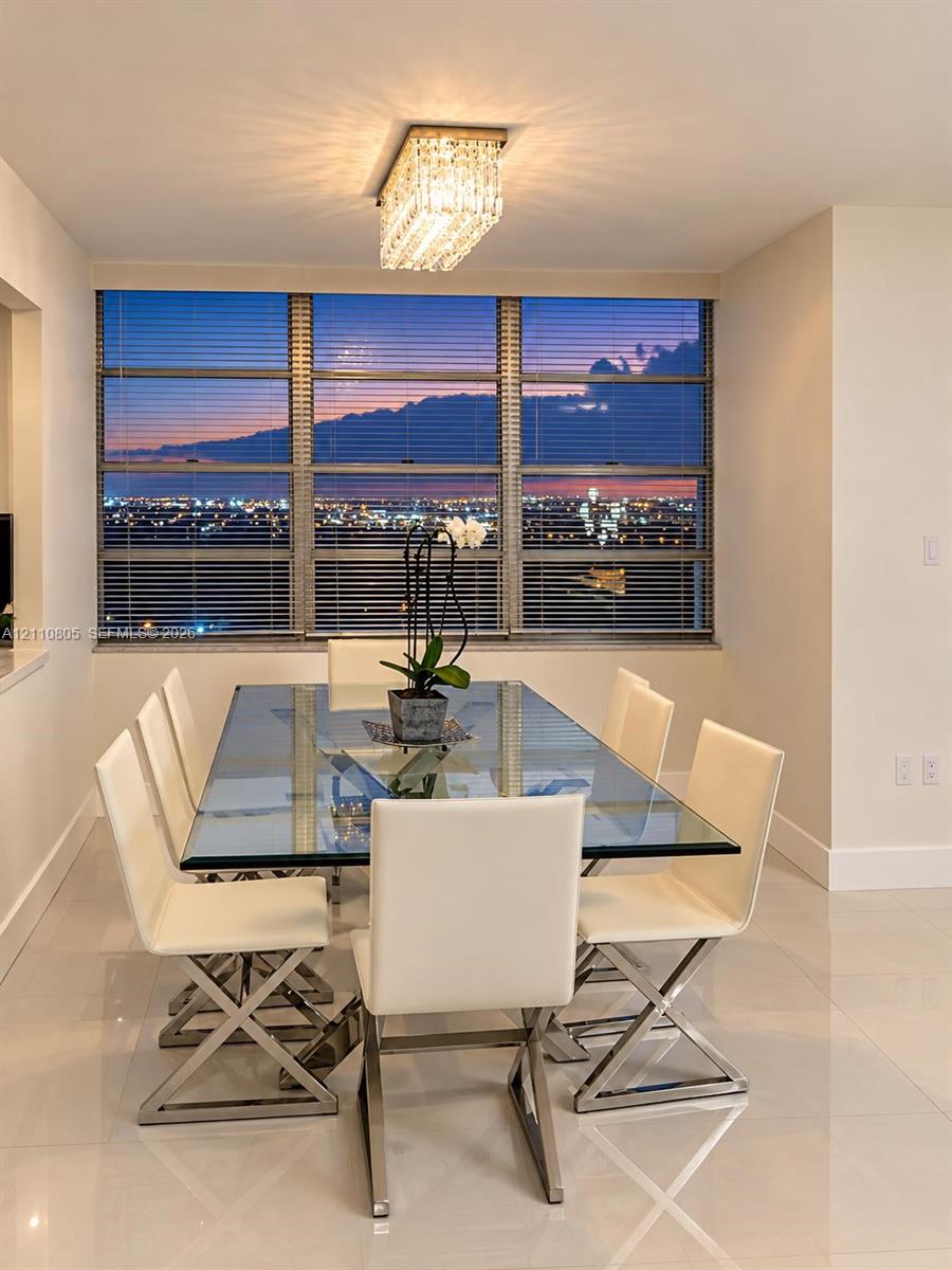 Large floor-to-ceiling windows featuring city-wide scenery, polished stone tile flooring, and a contemporary rectangular crystal-accented chandelier Large floor-to-ceiling windows featuring city-wide scenery, polished stone tile flooring, and a contemporary rectangular crystal-accented chandelier