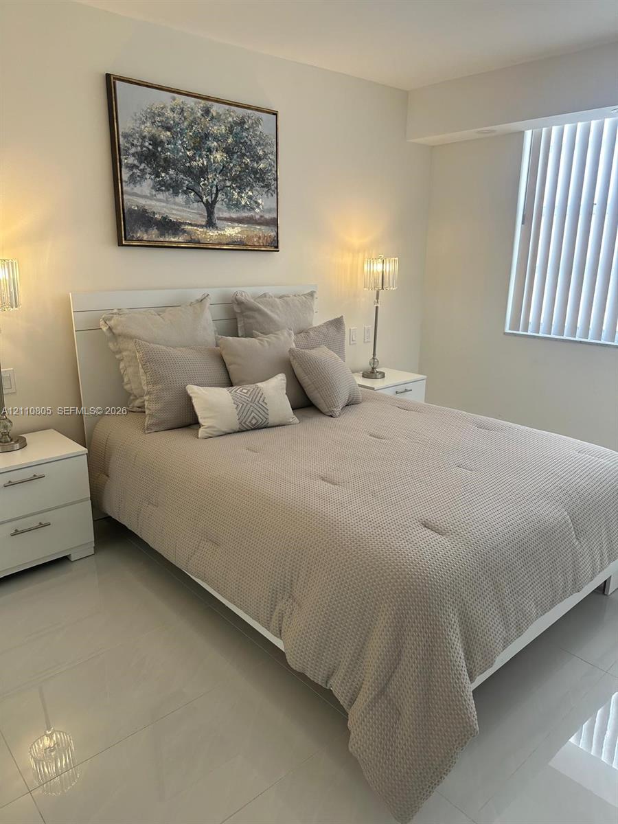 Neutral-toned tile flooring, recessed wall niche, and vertical window blinds