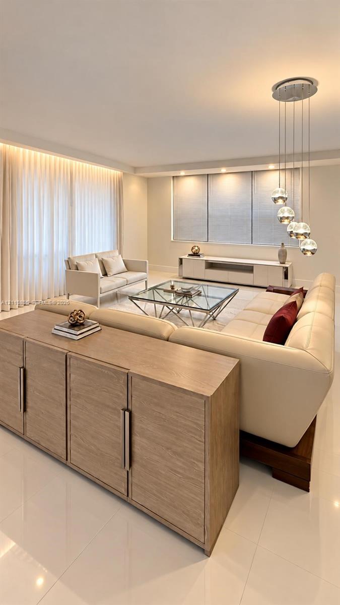 Living area featuring neutral-toned walls, high-gloss floor tile, recessed ceiling lighting, a modern multi-pendant light fixture, and built-in white cabinetry Living area featuring neutral-toned walls, high-gloss floor tile, recessed ceiling lighting, a modern multi-pendant light fixture, and built-in white cabinetry