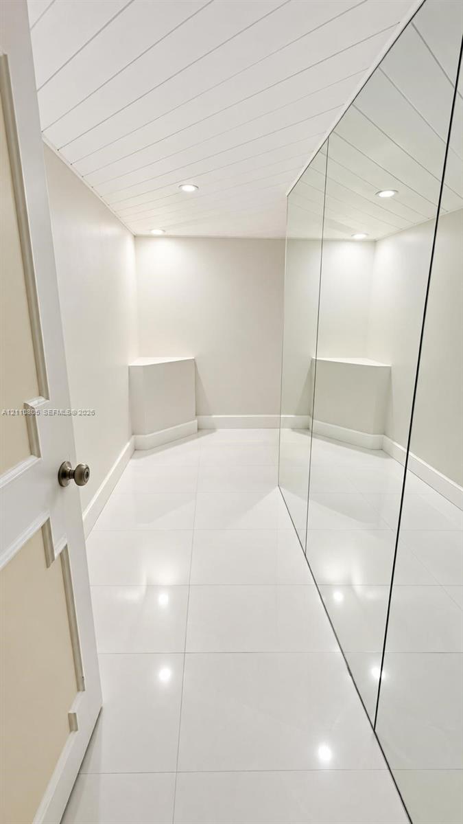 Glossy tile flooring, shiplap ceiling, full-length wall mirror, and recessed lighting