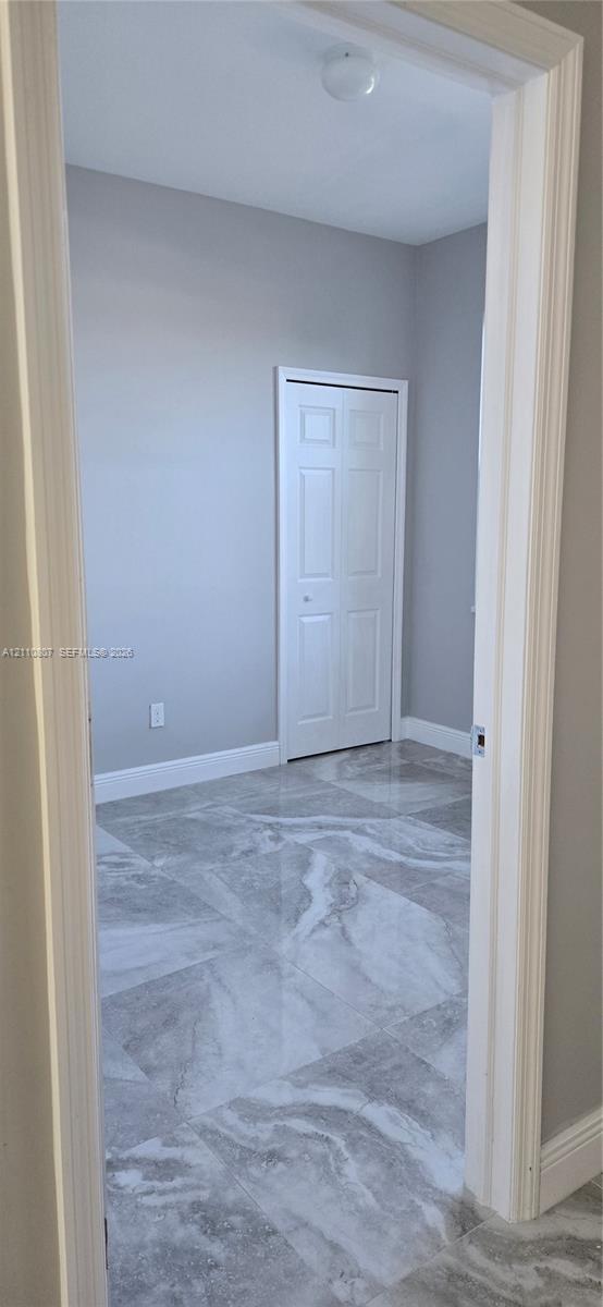 Interior room featuring large-format patterned stone-finish tile flooring, neutral wall paint, and a white six-panel closet door with a central light fixture
