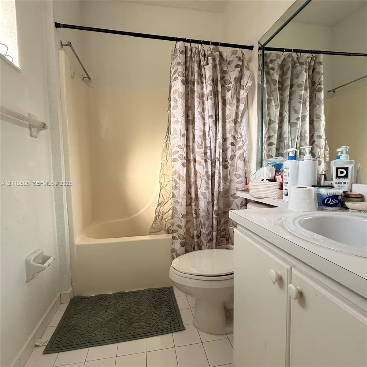 Bathroom featuring a white vanity cabinet with an integrated sink, a large wall-mounted mirror, and a tub-shower combination with a molded surround