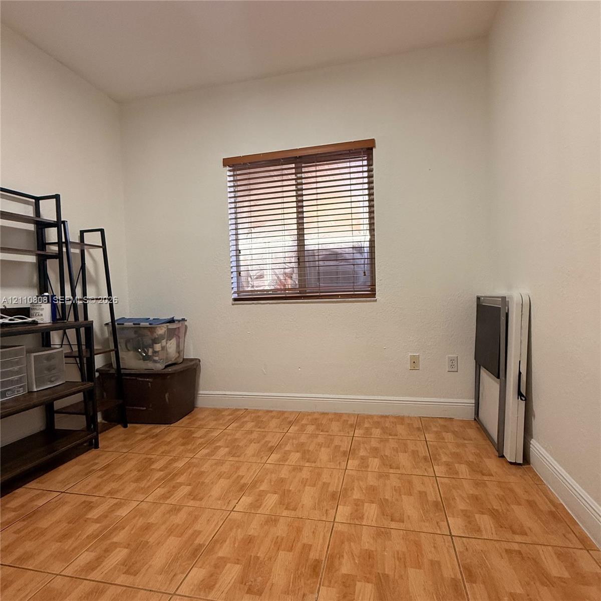 Interior room featuring wood-finish tile flooring and a window with horizontal blinds