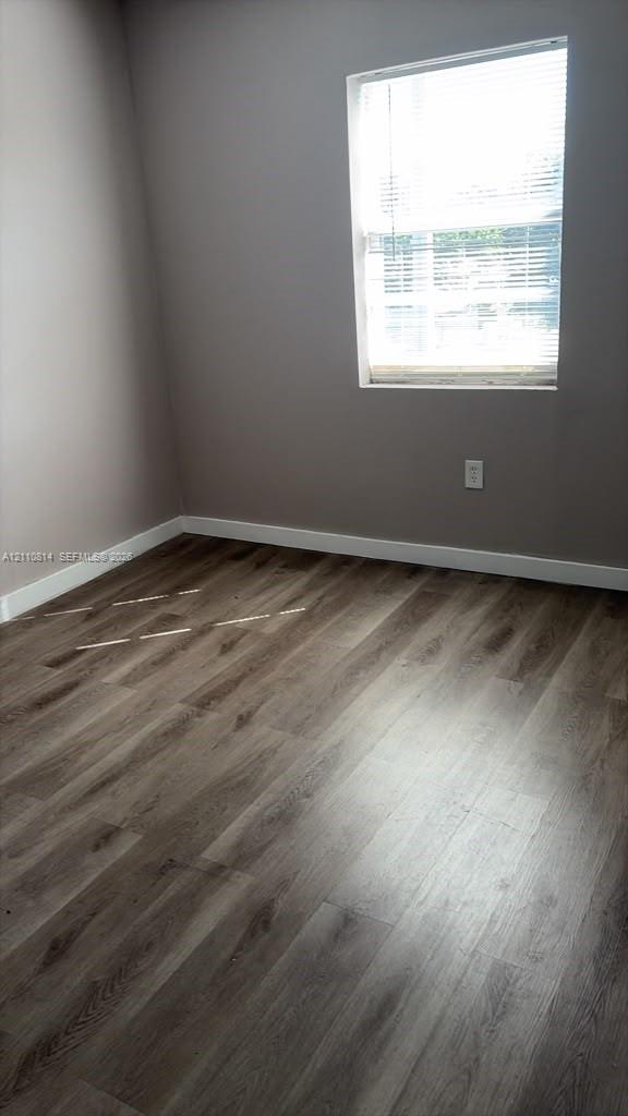 Room featuring neutral-toned walls, wood-finish flooring, and a single-pane window