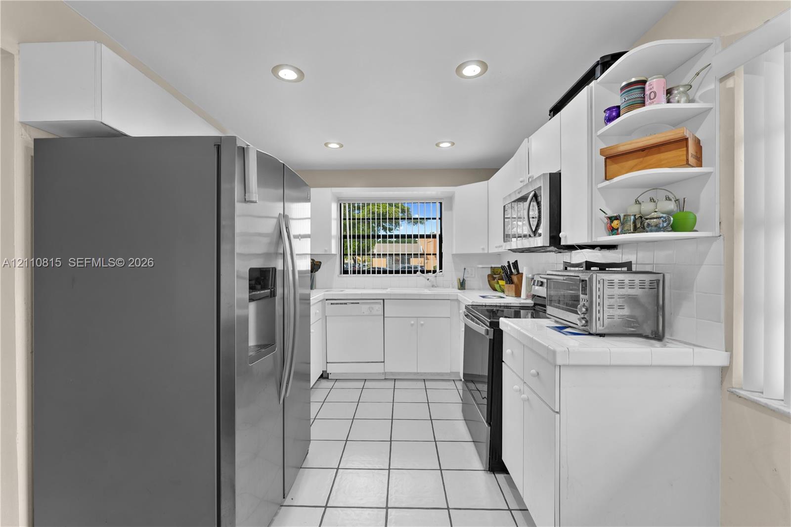 Kitchen featuring white cabinetry, stainless steel appliances, ceramic tile flooring, and recessed ceiling lighting