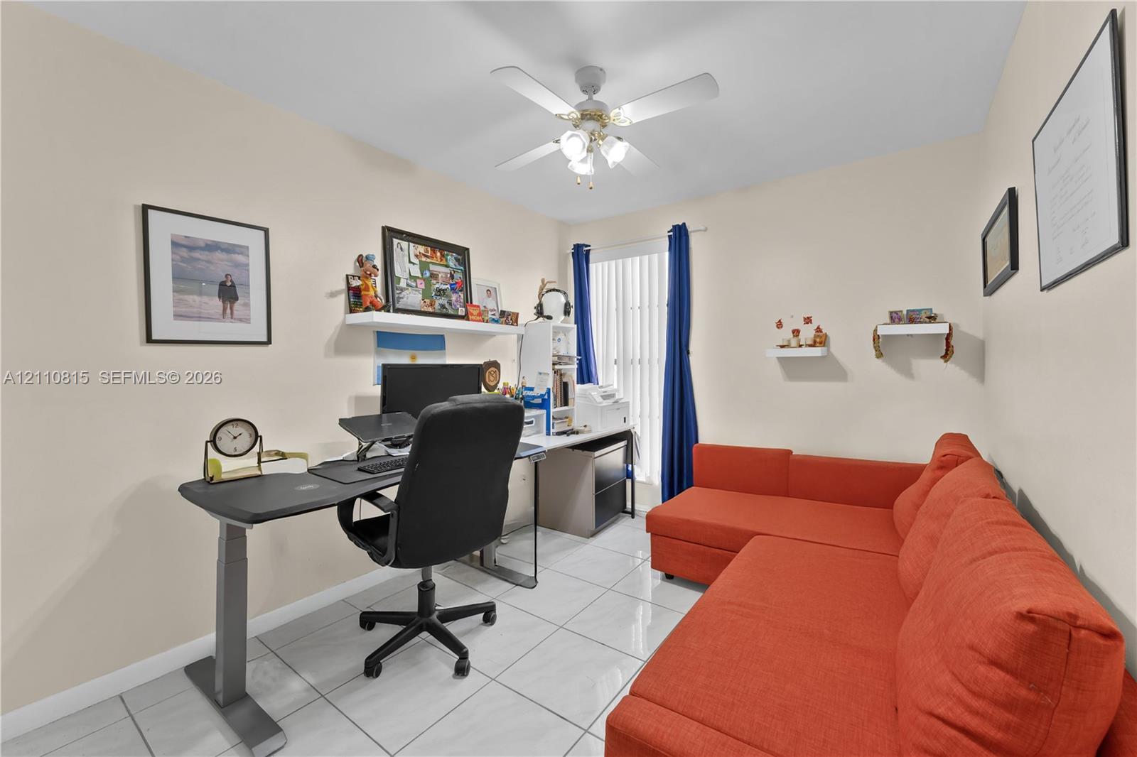 Room featuring large-format ceramic tile flooring, a central ceiling fan with integrated lighting, and a vertical window with neutral walls