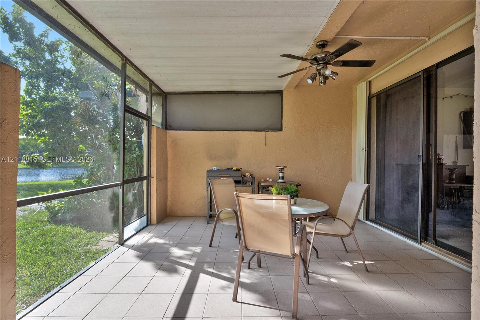 Screened-in patio featuring tiled flooring, a ceiling fan with integrated lighting, and direct access to the exterior through sliding glass doors