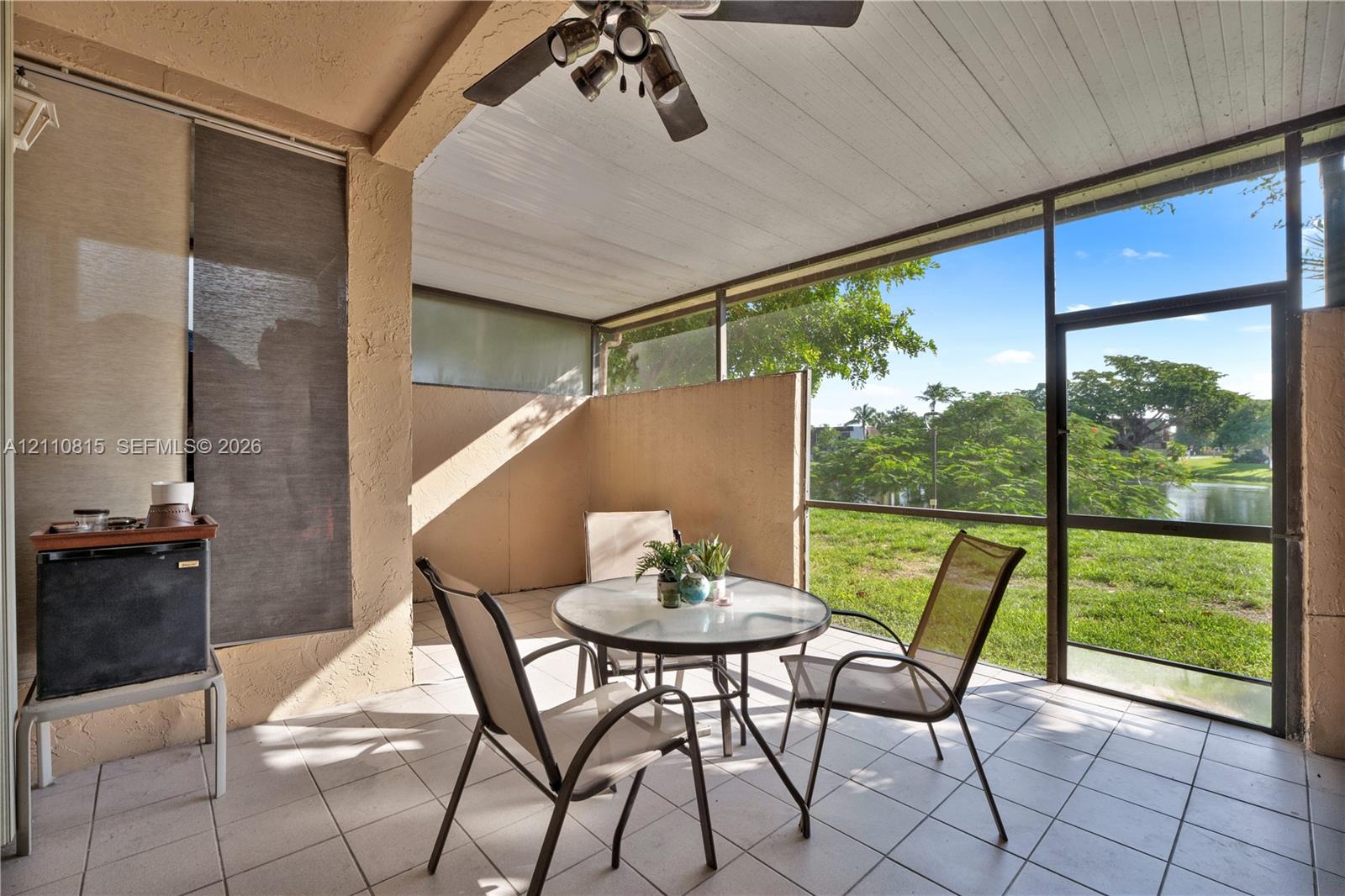 Screened-in patio featuring white tile flooring, beadboard ceiling, overhead ceiling fan, and structural enclosure with aluminum framing