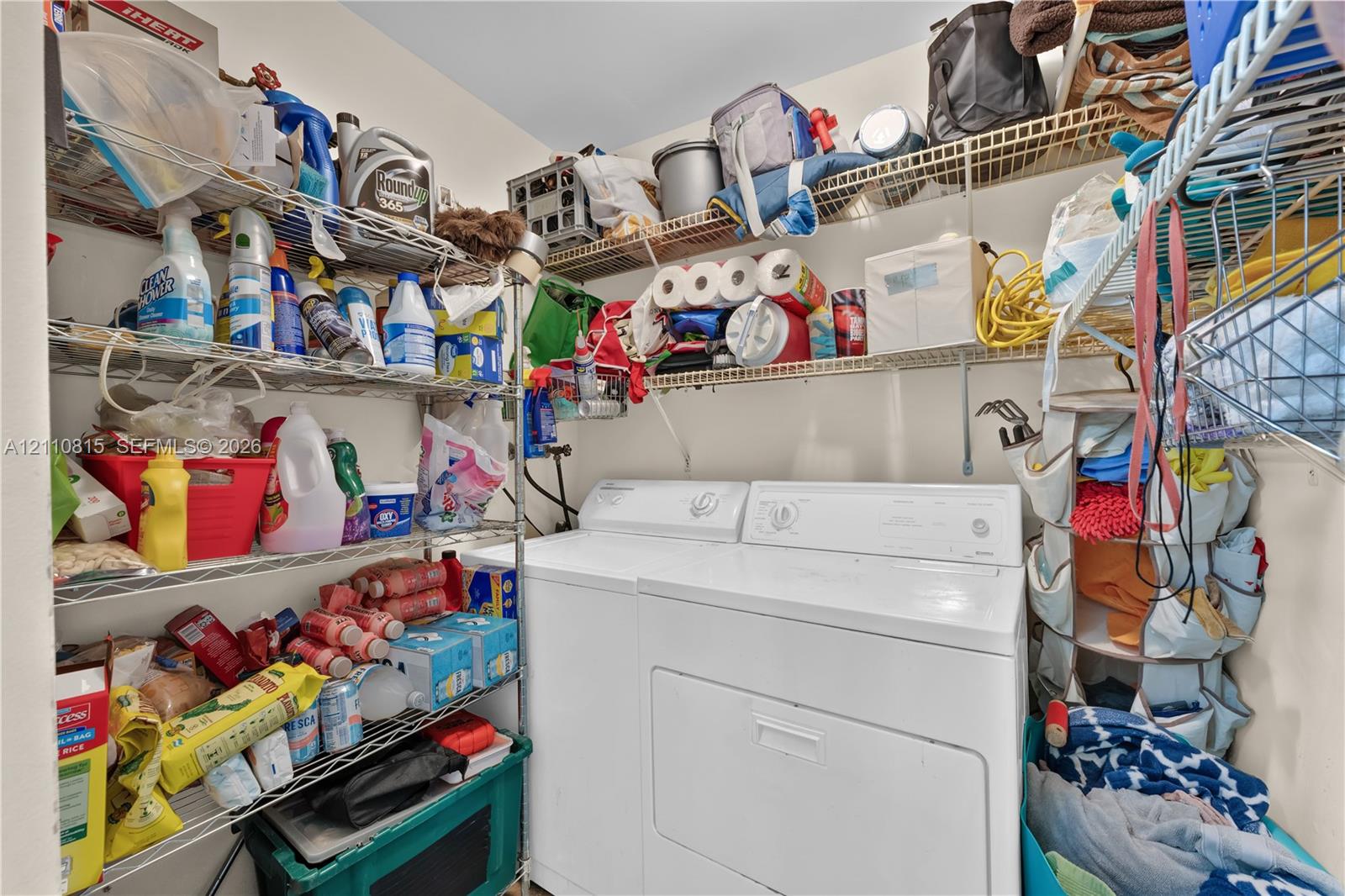 Laundry area featuring white top-load washer and dryer with multi-level wire shelving