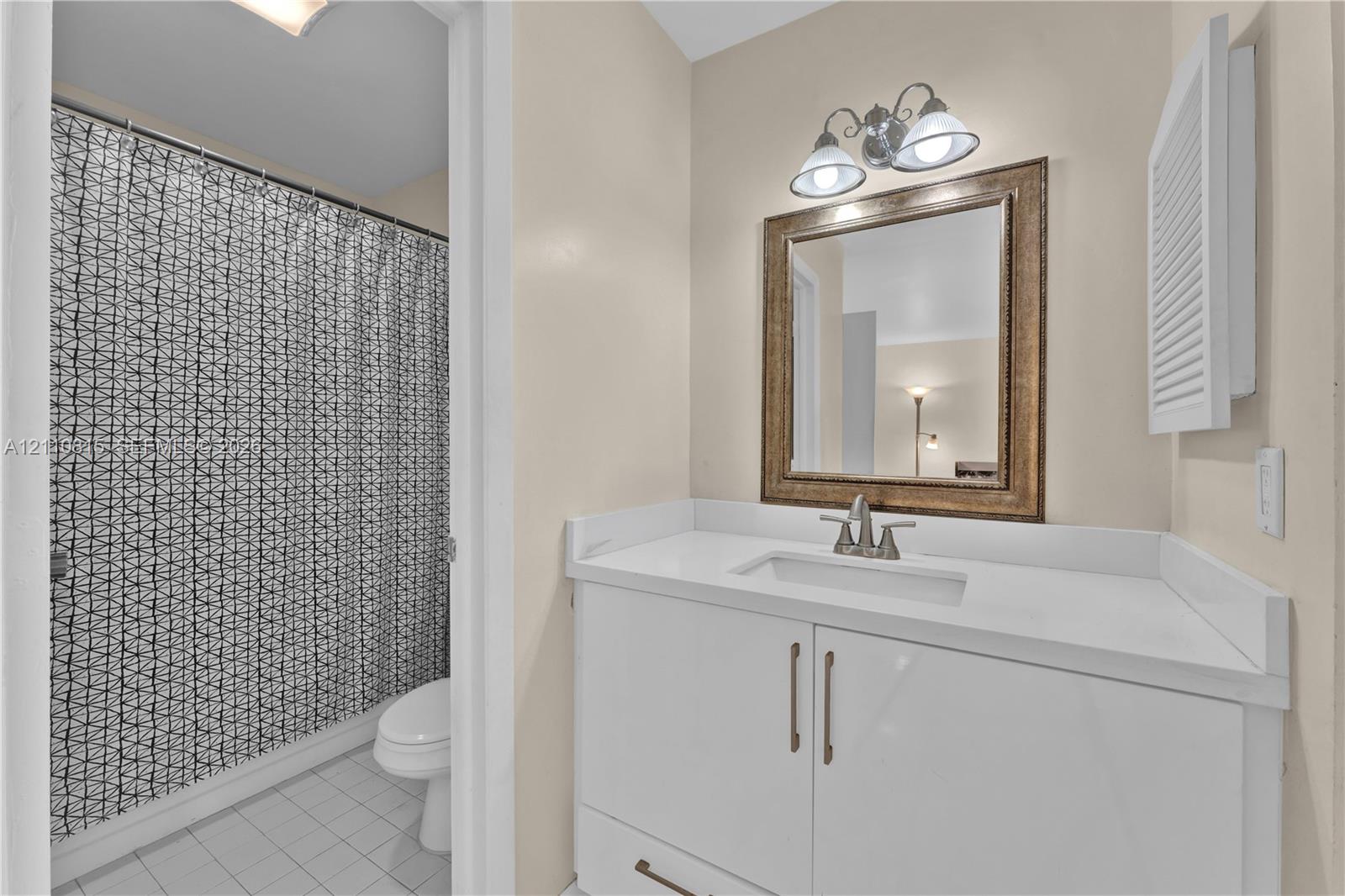 White vanity with integrated rectangular sink, solid surface countertop, two-light vanity fixture, and recessed medicine cabinet