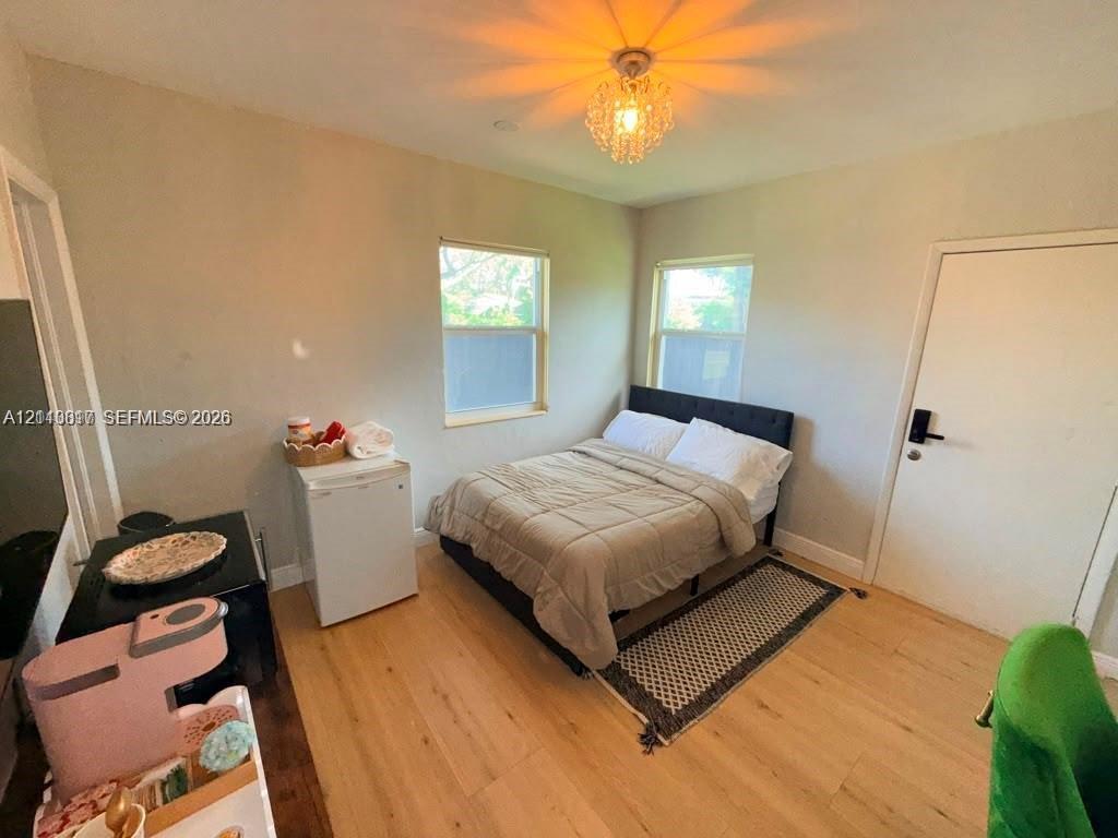Light-filled room featuring wood-finish flooring, two dual-pane windows, and a decorative crystal flush-mount light fixture