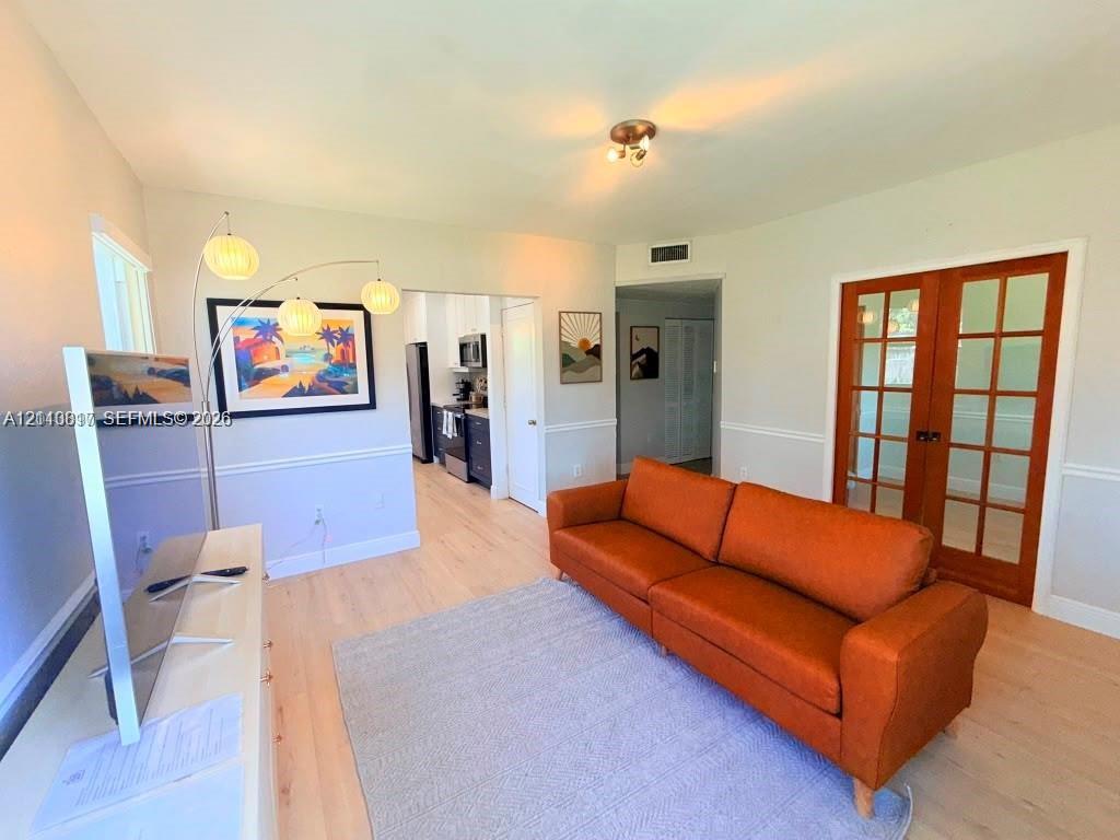 Light-toned wood-finish flooring, white chair rail molding, and French doors with wood frames