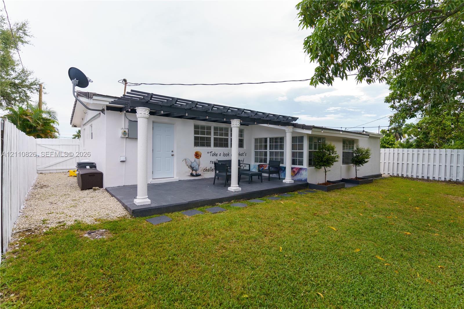 Exterior patio featuring a pergola with classic columns, concrete surfacing, fenced yard, and gravel side path