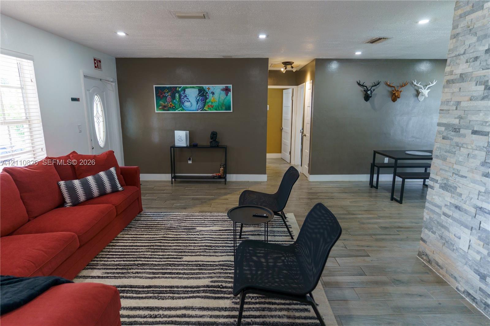 Open-concept area featuring stone-clad accent wall, recessed lighting, and wood-finish flooring Open-concept area featuring stone-clad accent wall, recessed lighting, and wood-finish flooring