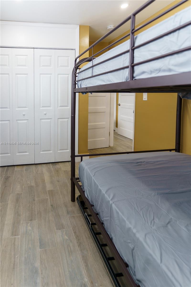 Wood-finish flooring, white bi-fold closet doors, and interior paneled doors
