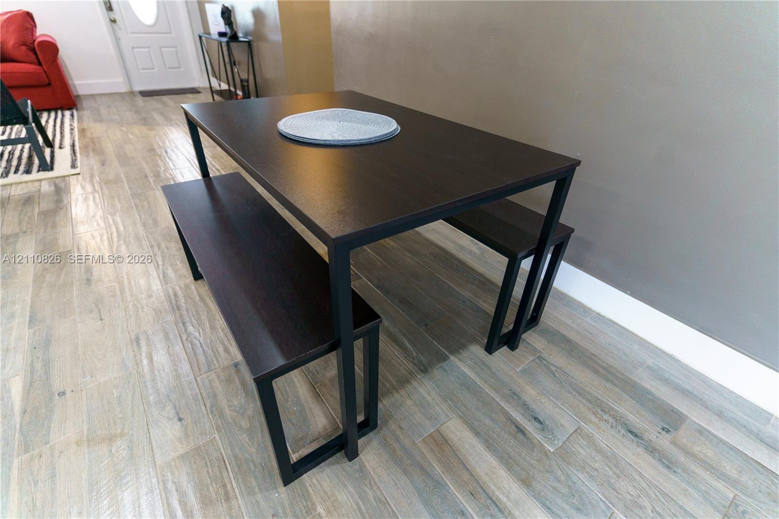 Wood-finish plank flooring featuring a neutral gray palette and a paneled entry door with an oval glass insert