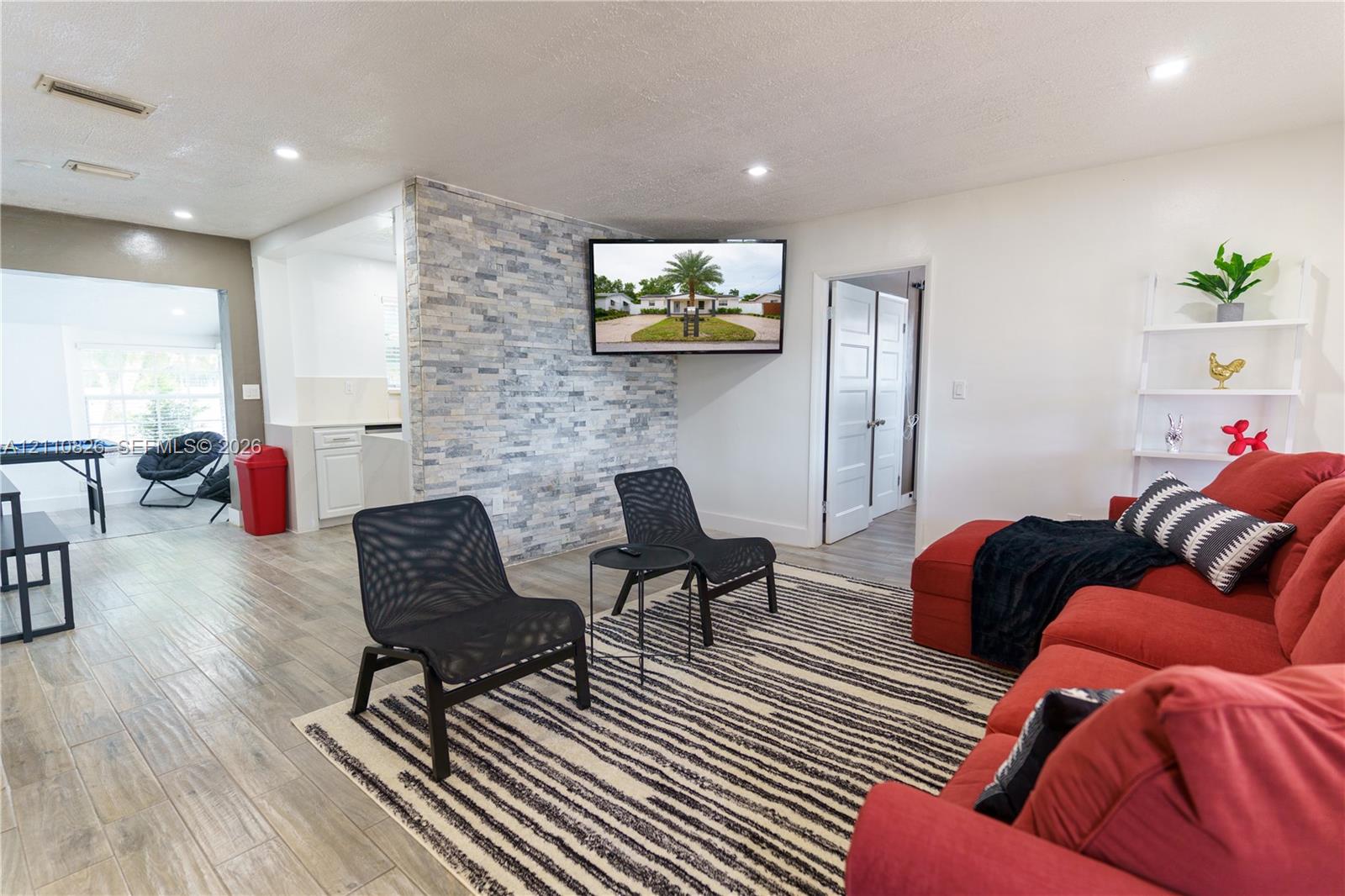 Living area featuring wood-finish flooring, a stacked stone accent wall, and recessed lighting